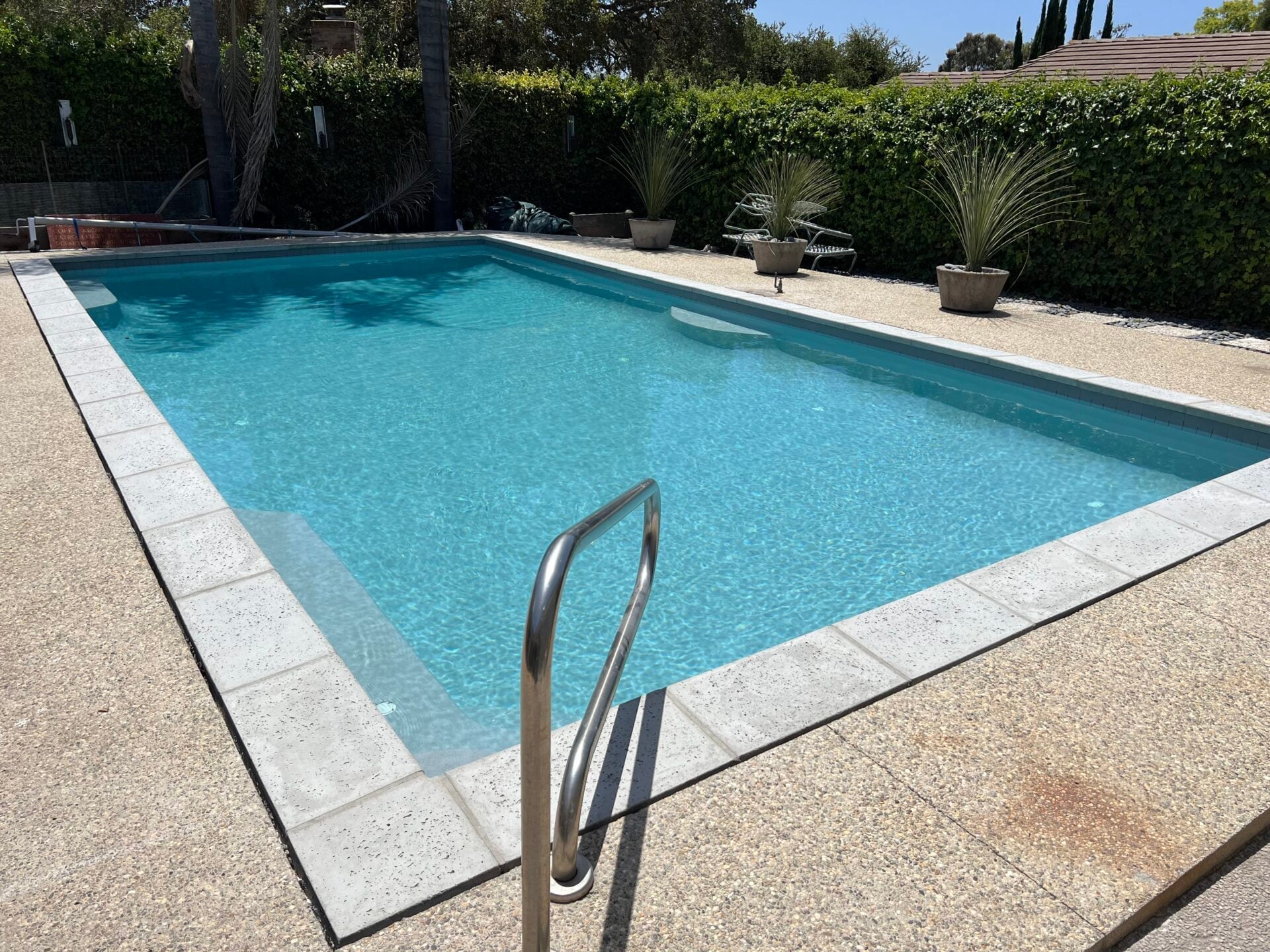 Pool with new coping and a stainless steel handrail at the steps