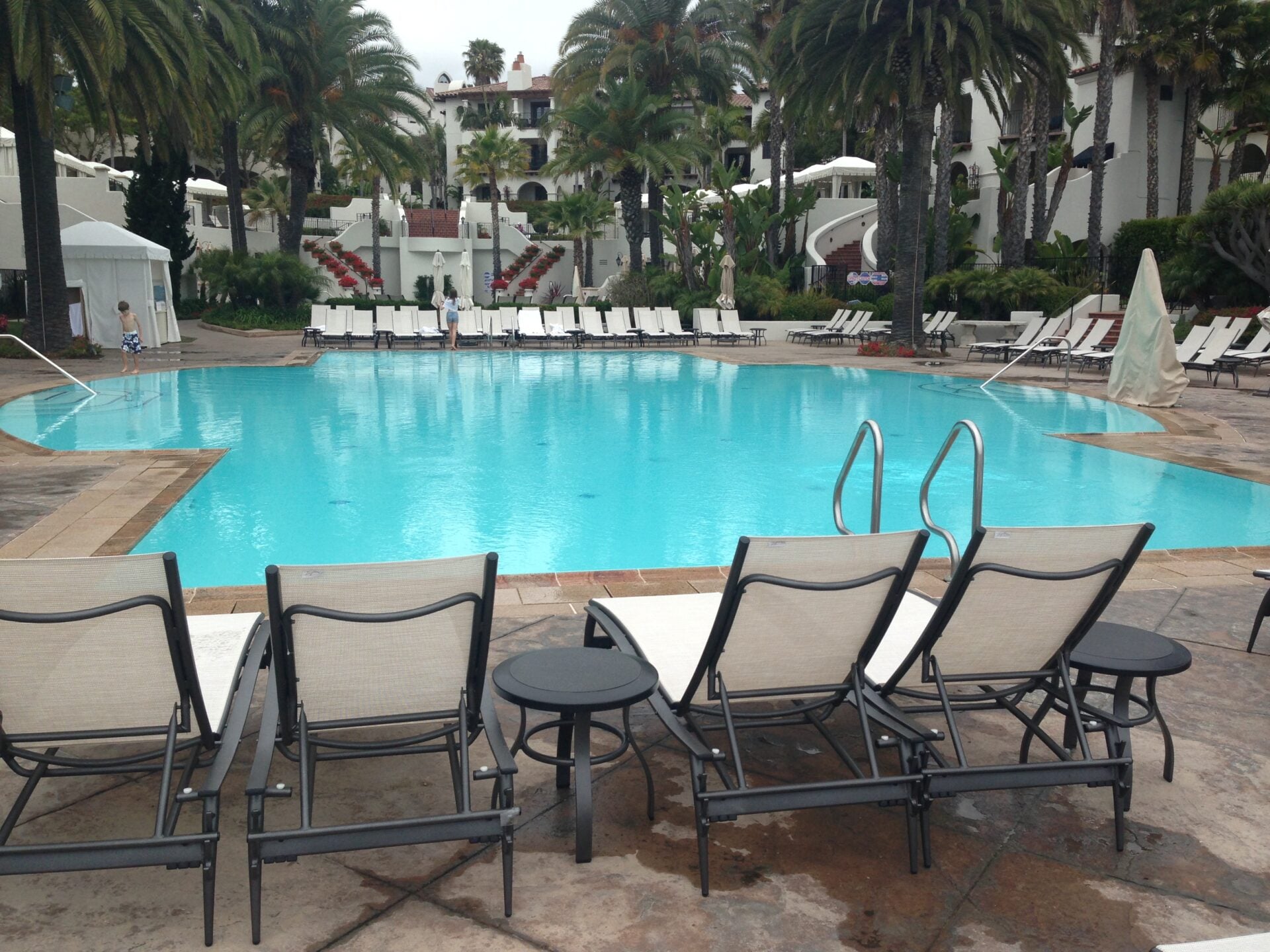 Resort pool lined with white lounge chairs and cabanas