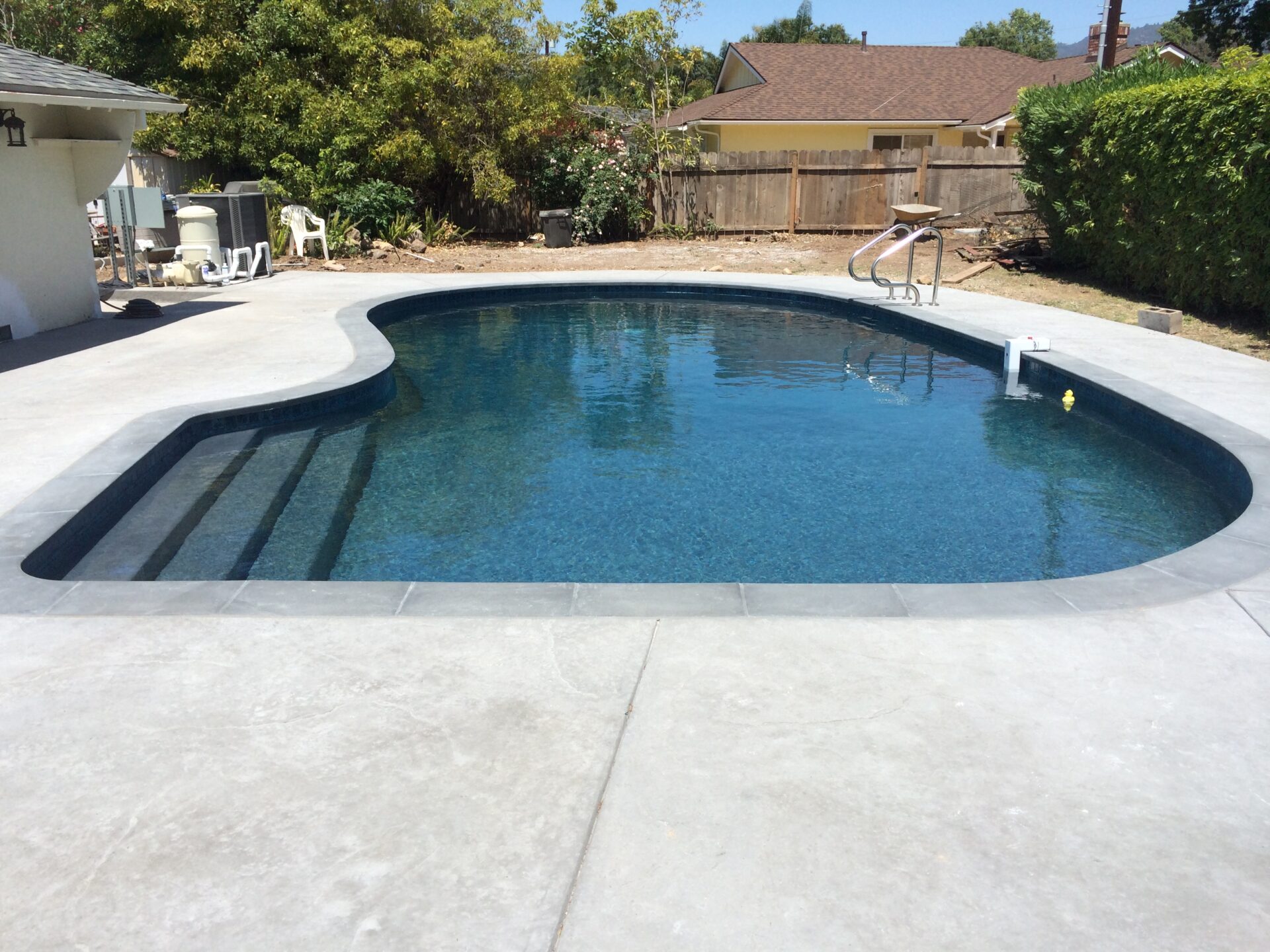 Backyard pool with a dark fiberglass finish and wide entry steps