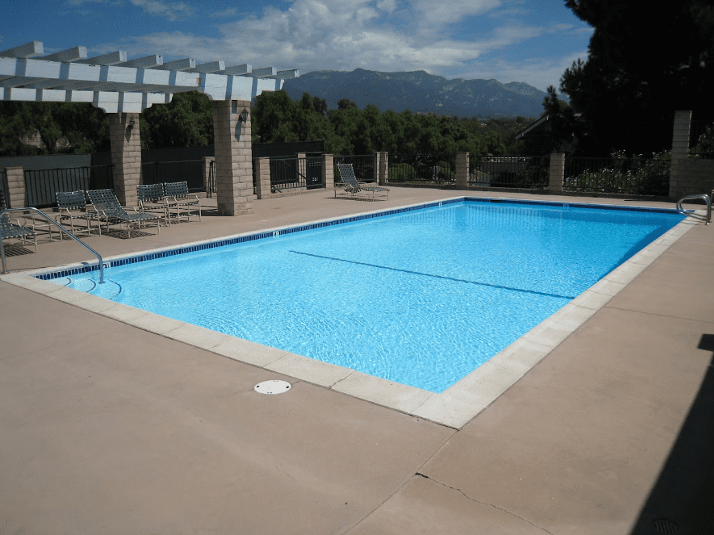 Rectangular pool under a pergola with mountains behind resurfaced by Aqua Creations