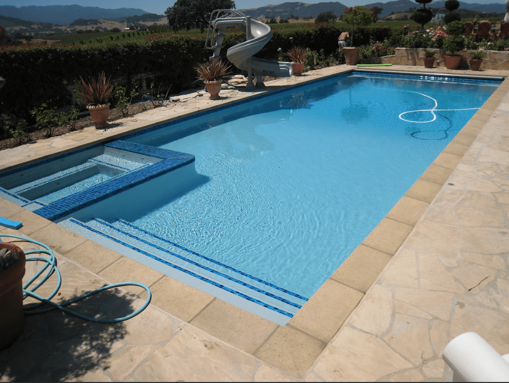 Rectangular pool with a waterslide at the edge resurfaced by Aqua Creations